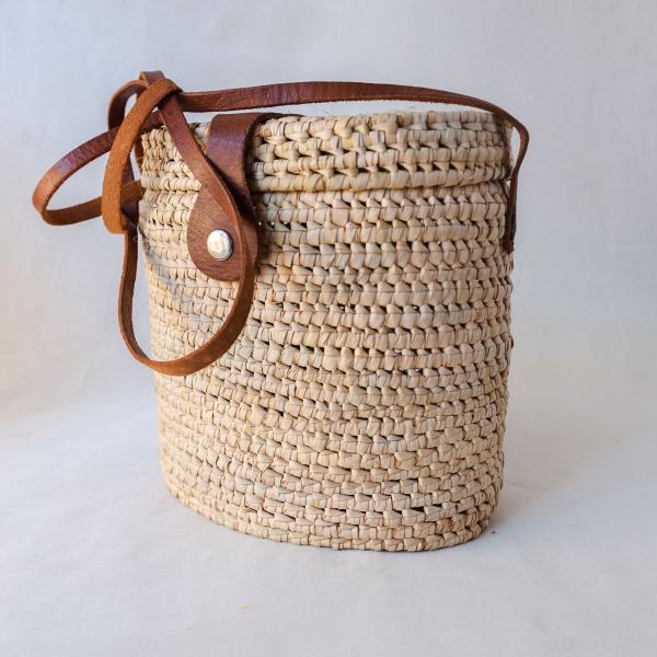 Product image of a natural woven rectangular bag with a leather strap and clasp 