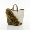 Woven handbag with a decorative pom-pom on a light background
