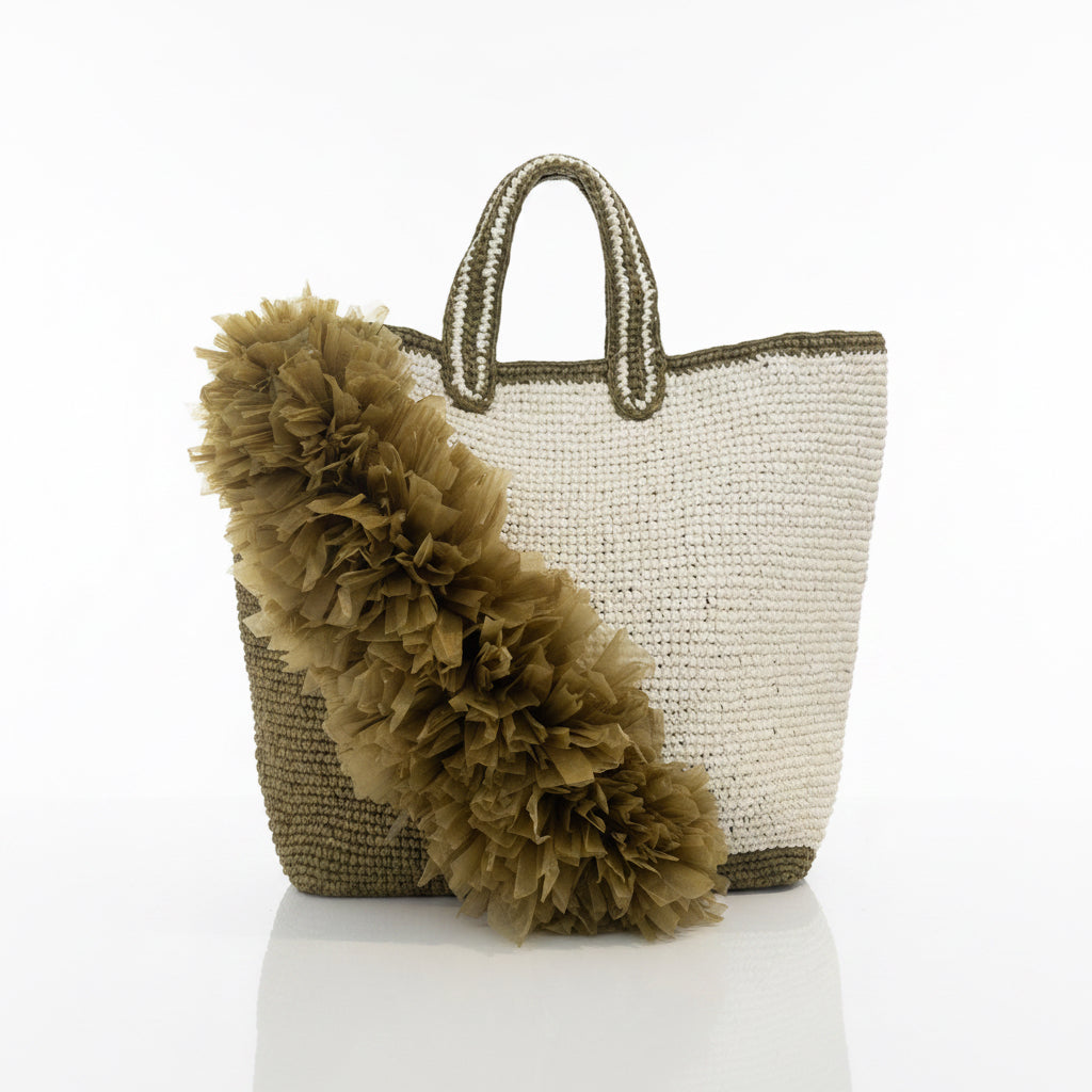 Woven handbag with a decorative pom-pom on a light background