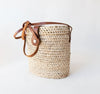 Product image of a natural woven rectangular bag with a leather strap and clasp 
